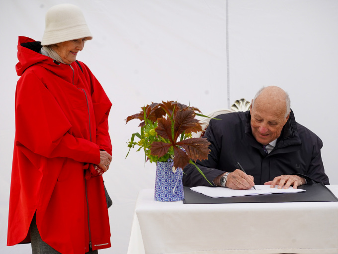 Kong Harald og Dronning Sonja signerer på et eget papir. Senere skal navnetrekkene overføres til Kongesteinen. Foto: Liv Anette Luane, Det kongelige hoff